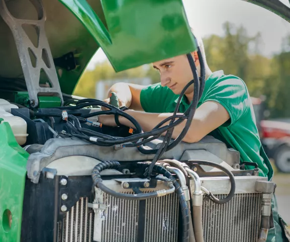 Man aan het werken aan tractor met motorkap open